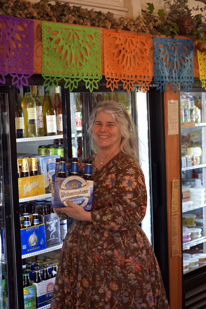Teresa Torbett, Besitzerin der Columbia Mercantile 1855, mit einem Sechserträger Weihenstephaner Bier vor dem Kühlregal des Ladens.