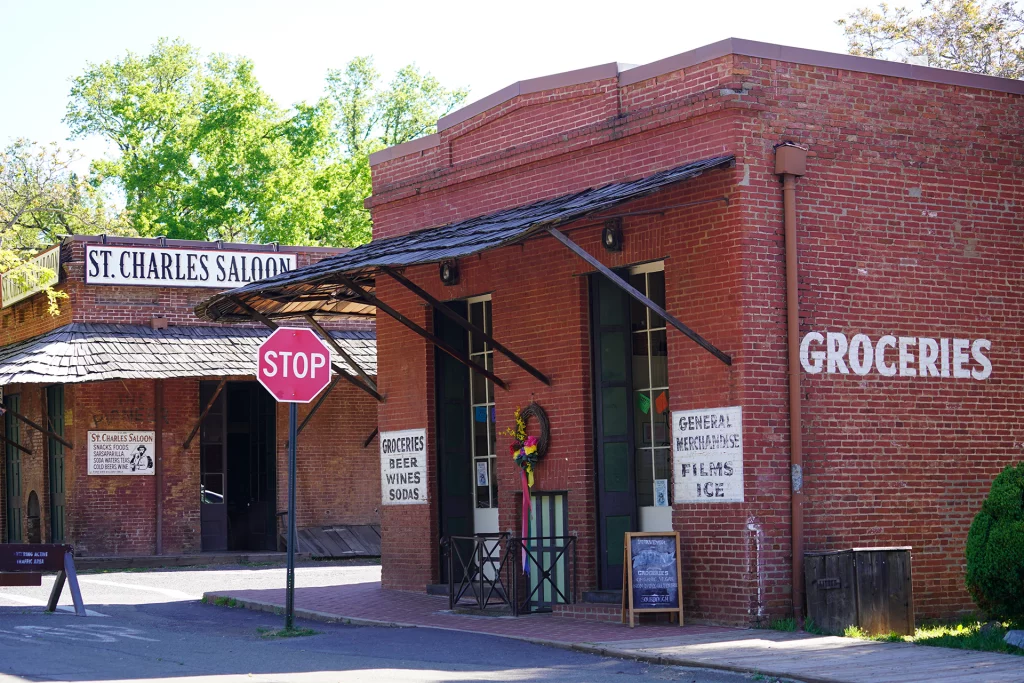 Backsteinfassaden mit historischen Schildern der St. Charles Saloon und eines Gemischtwarenladens in Columbia, Kalifornien