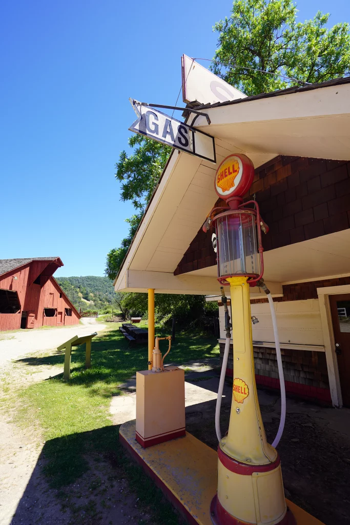 Historische gelbe Shell-Zapfsäule mit Glasdom und Gas-Schild vor einem alten Holzgebäude im Bridgeport Historic District, Kalifornien