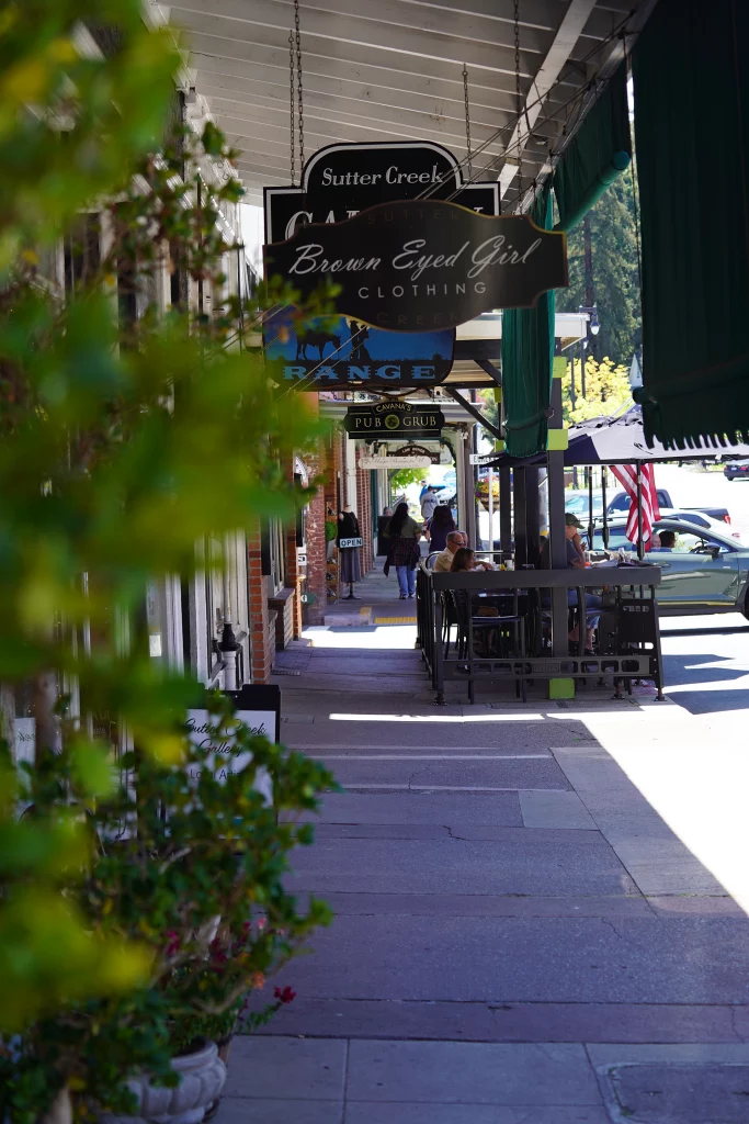 Überdachter Gehweg mit Shops, Straßencafés und Schildern in der Altstadt von Sutter Creek, Kalifornien