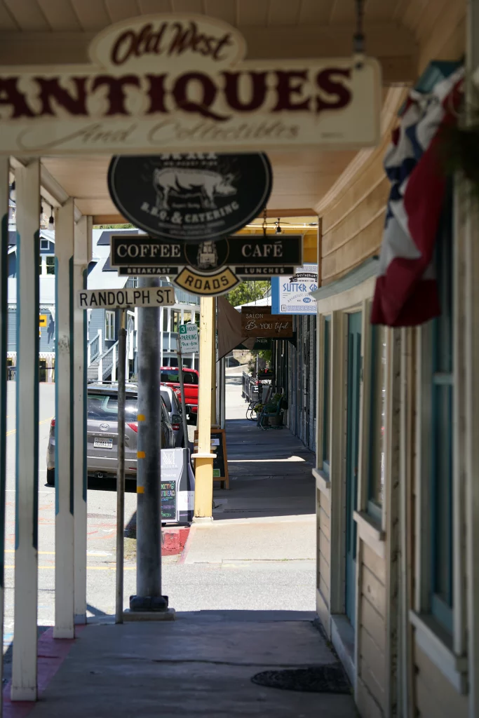Überdachter Bürgersteig mit Straßenschildern, Ladenfassaden und Café-Schildern in Sutter Creek, Kalifornien