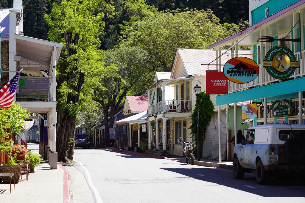 Hauptstraße von Downieville, Kalifornien, mit historischen Gebäuden, kleinen Shops, US-Flagge und geparktem Oldtimer