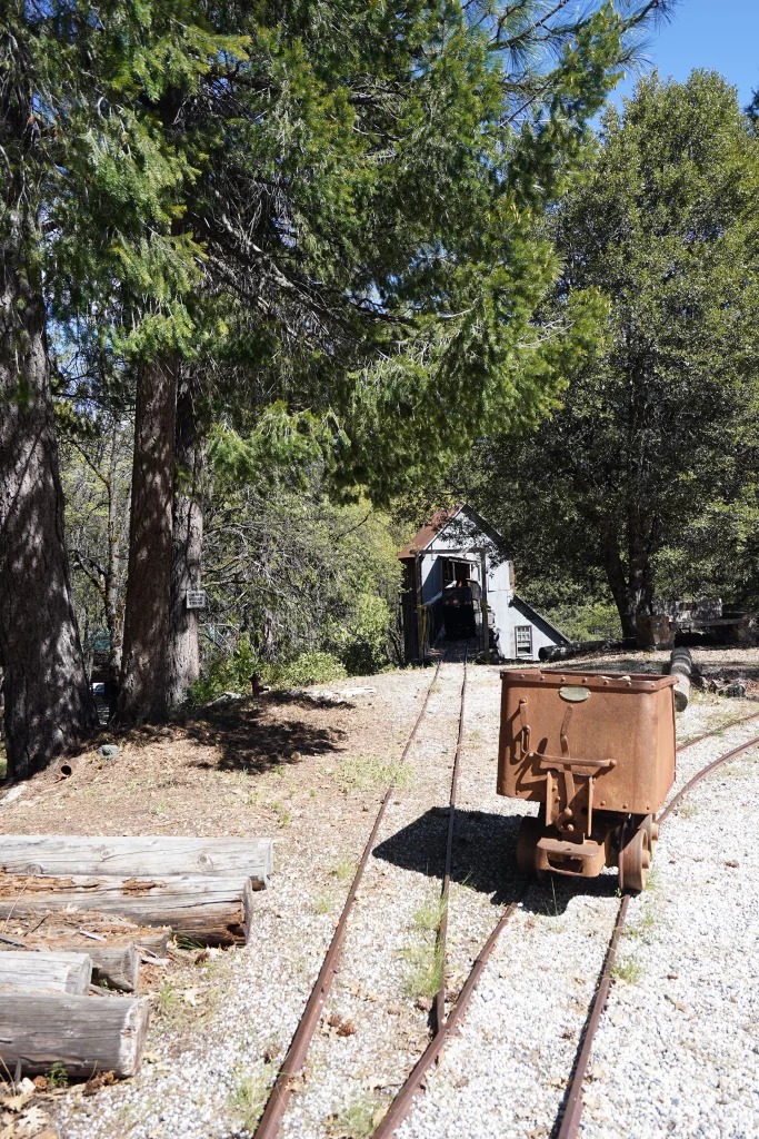 Historischer Minenwagen auf Schienen im Wald vor dem Stolleneingang der Kentucky Portal Mine in Sierra City, Kalifornien.