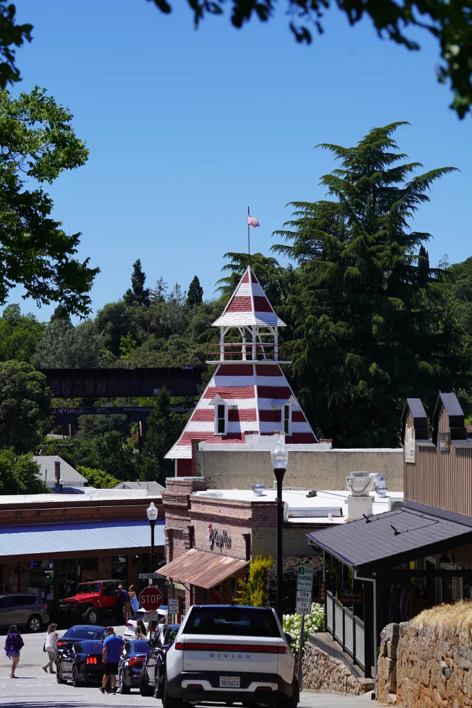 Bell Tower auf der Main Street von Placerville, Kalifornien, mit US-Flagge und Fußgängern im Vordergrund