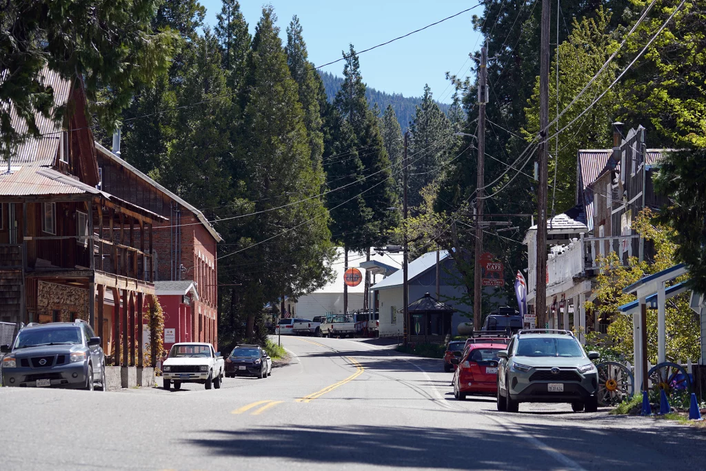 Blick auf die Hauptstraße von Sierra City, Kalifornien, mit historischen Gebäuden, parkenden Autos und Nadelbäumen im Hintergrund