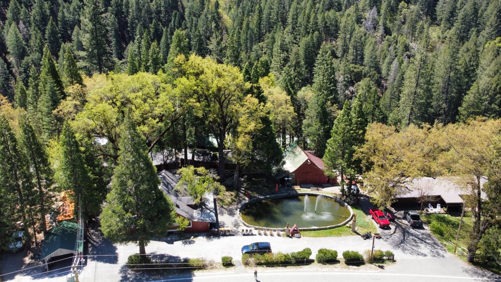 Drohnenaufnahme des Sierra Pines Resort mit Teich, Bäumen und Gebäuden, direkt am Highway 49 in Sierra City, Kalifornien.