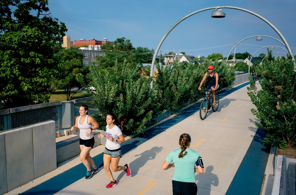 Jogger und Radfahrer auf dem erhöhten 606 Trail in Chicago, umgeben von Stadtgrün und moderner Infrastruktur.