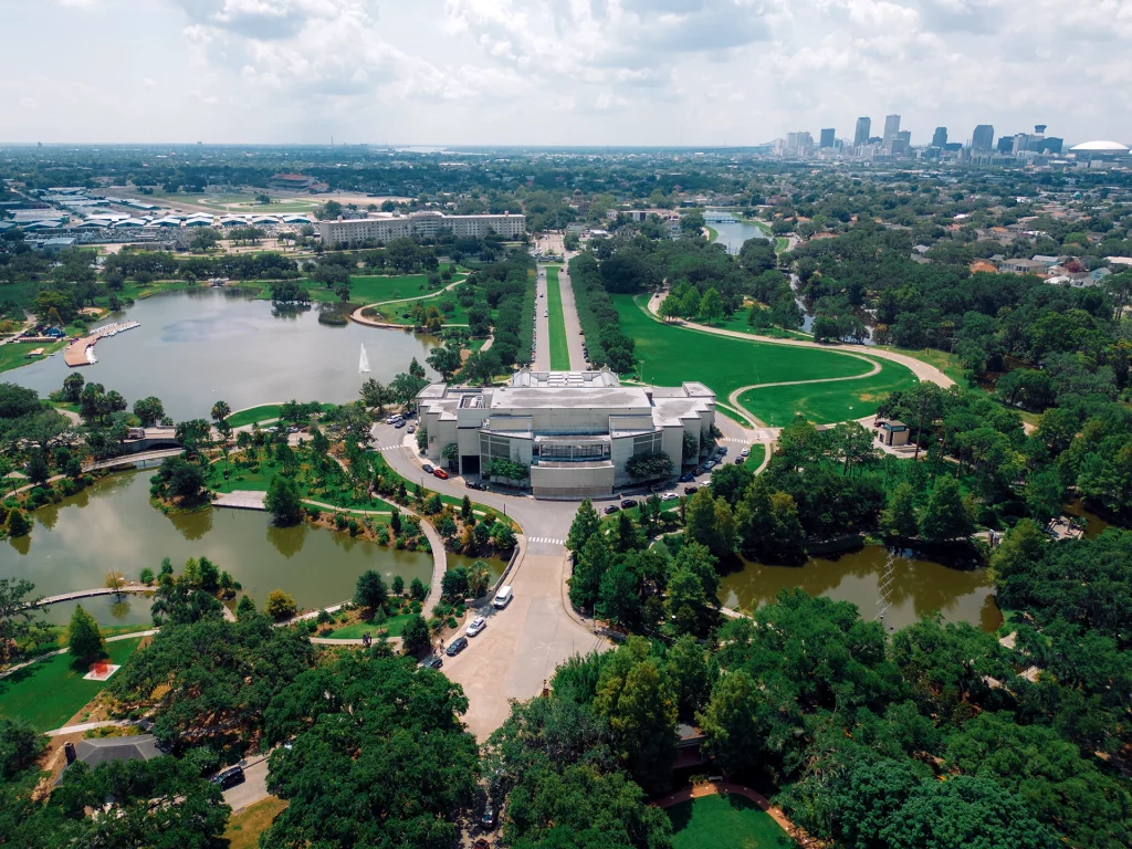 Luftaufnahme des City Park in New Orleans mit Grünflächen, Seen und der Skyline im Hintergrund.