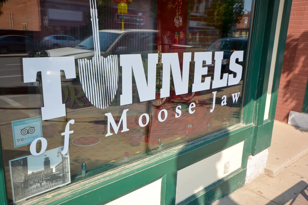 Eingang zu den Tunnels of Moose Jaw mit weißer Aufschrift auf Schaufensterscheibe