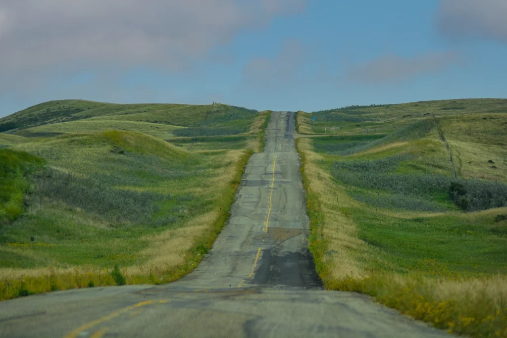Verlassene Landstraße schlängelt sich durch hügelige Prärie am Badlands Parkway in Saskatchewan, Kanada