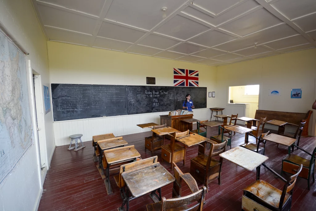 Innenraum der historischen Paisley Brook School mit Holzbänken und Union-Jack-Flagge