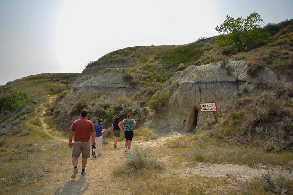 Gruppe von Wanderern vor den Sam Kelly Outlaw Caves in den Hügeln der Prärie von Saskatchewan