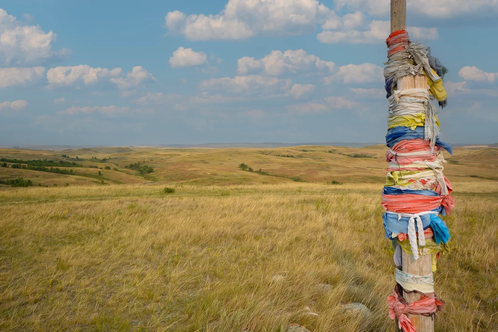 Gebetsfahnen an einem Holzpfahl in der weiten Prärie des East Block im Grasslands National Park, Saskatchewan
