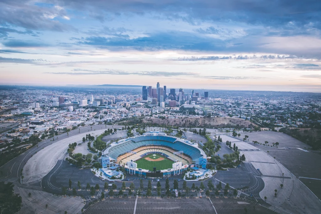 Aerial view of Dodger Stadium and the Los Angeles skyline under a cloudy sky.