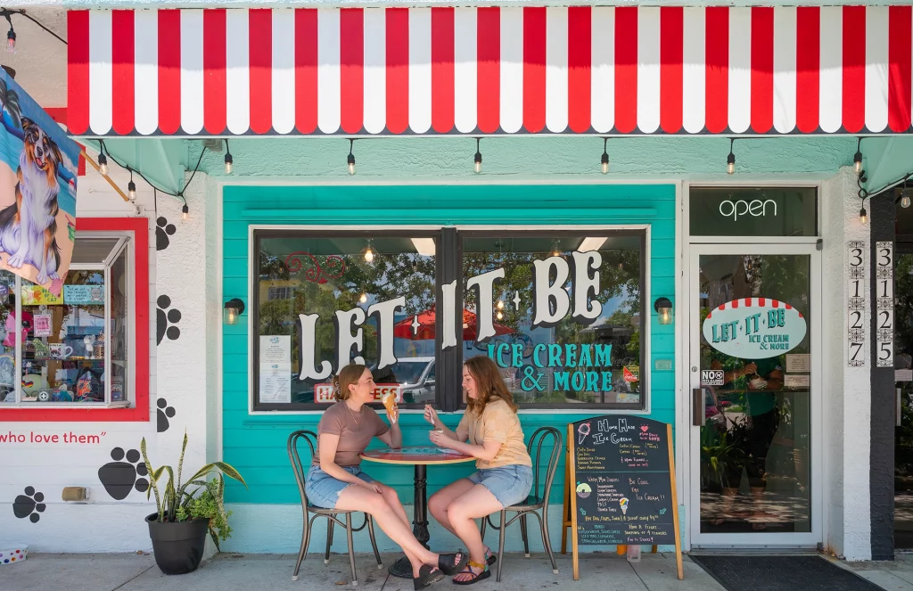 Zwei Frauen genießen Eiscreme vor einem bunten Café in Gulfport, Florida.