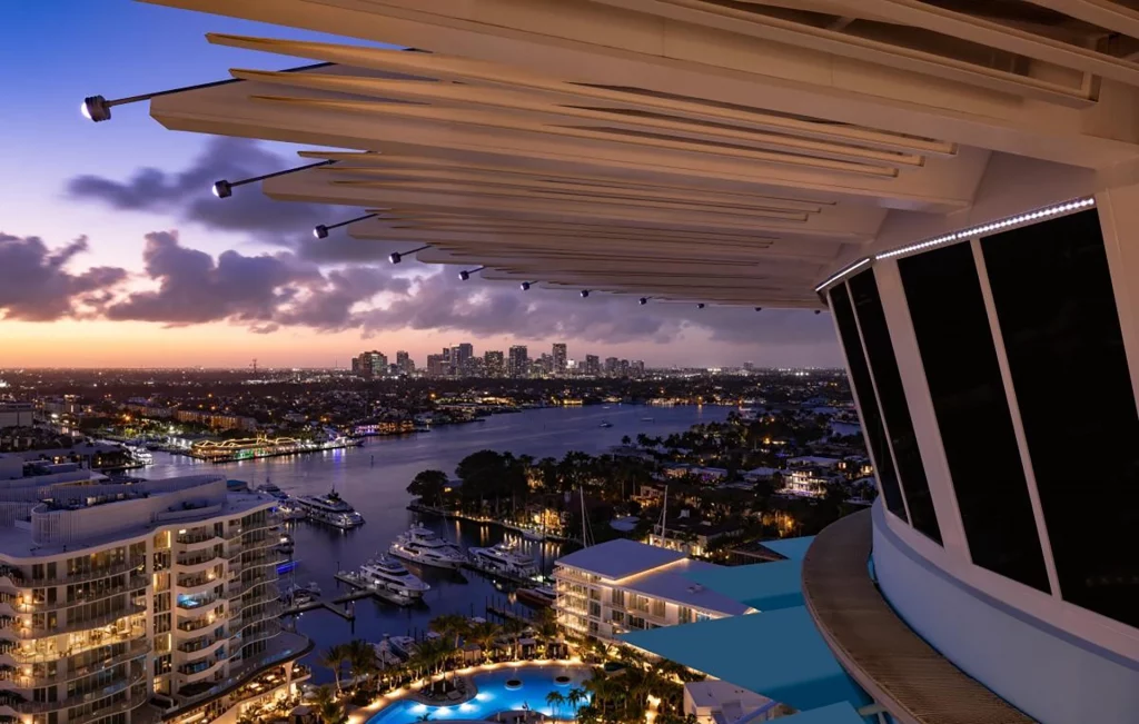 Blick von einer Dachterrasse über Fort Lauderdale bei Sonnenuntergang, mit Wasserwegen, Booten und Skyline.
