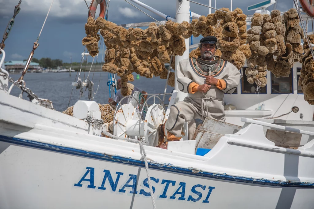 Traditioneller Schwammtaucher in Tarpon Springs auf einem Boot mit Natur-Schwämmen.