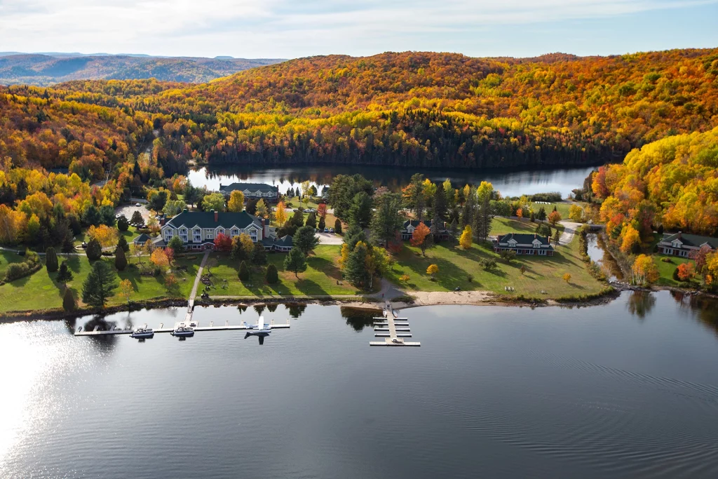 Luftaufnahme des Resorts Auberge du Lac-à-l’Eau-Claire, umgeben von herbstlich buntem Wald in der Region Mauricie, Québec.