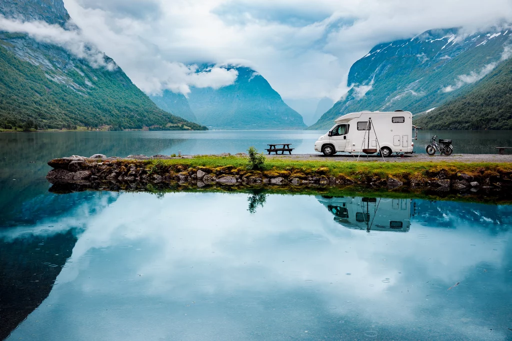 Wohnmobil am Fjord in Norwegen, Spiegelung im Wasser mit Bergen und Wolken im Hintergrund