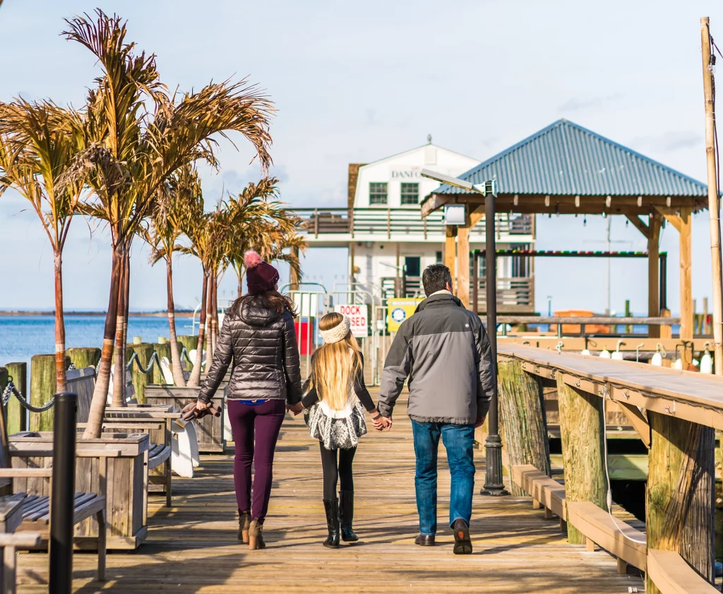 Familie spaziert Hand in Hand über das Dock von Port Jefferson mit Blick auf den Long Island Sound.