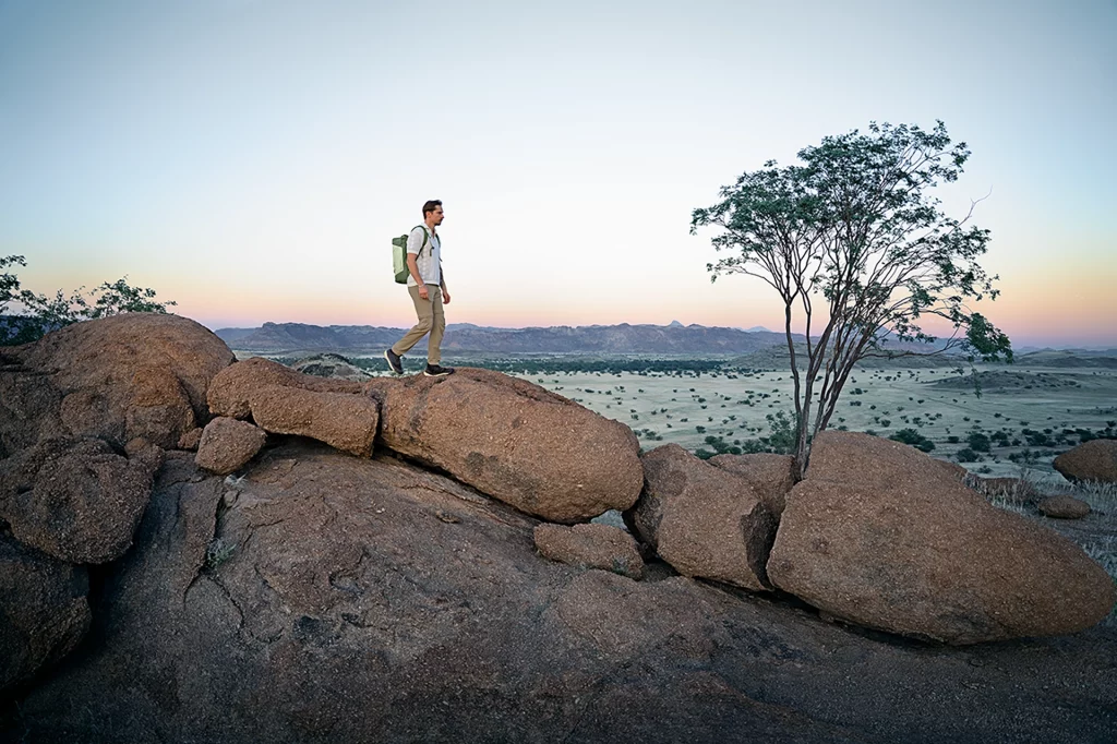Mann mit Deuter Duffel Pro Roller als Rucksack-Variante wandert über Felsen in Namibia.