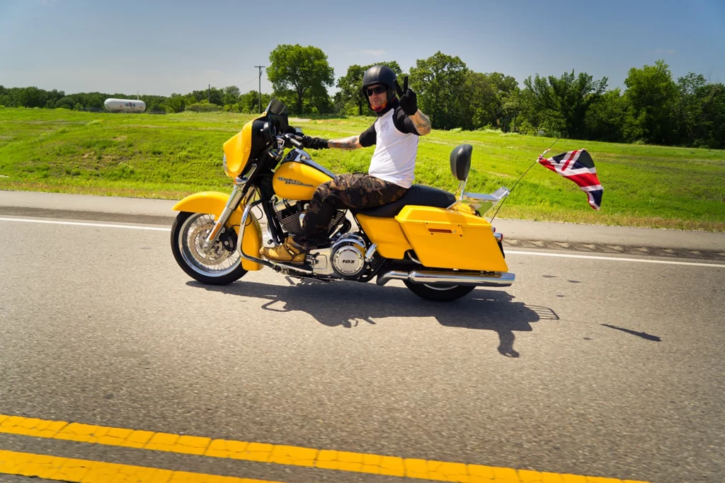 Motorradfahrer mit gelbem Bike und Union-Jack-Flagge fährt auf der Route 66.