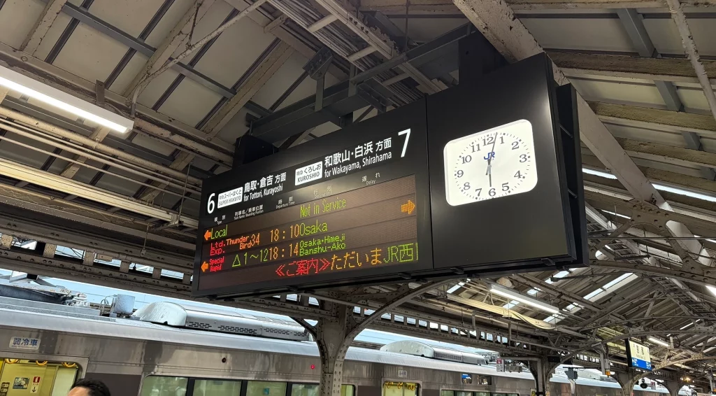 Elektronische Anzeigetafel mit Abfahrten am Bahnhof in Osaka, Japan.