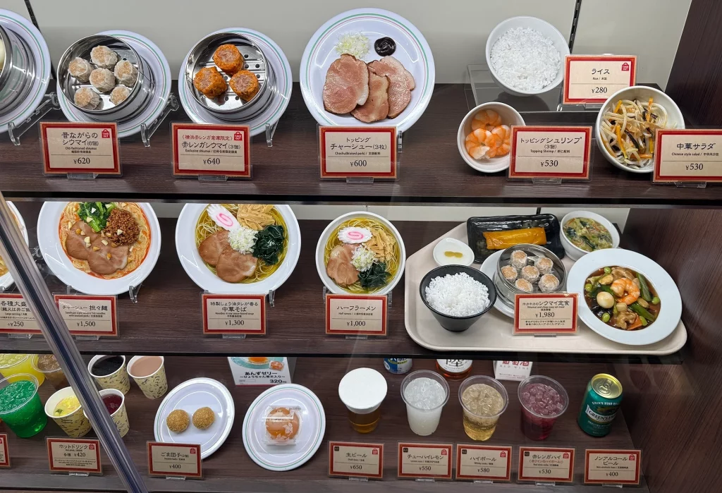 Auslage mit japanischen Ramen-Gerichten, Dim Sum und Getränken in einem Restaurant in Japan.