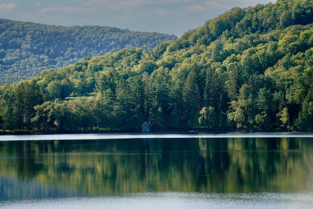 Blick auf den Lac Ouimet in Mont-Tremblant, umgeben von dichten Wäldern und Hügeln, gespiegelt im klaren Wasser.