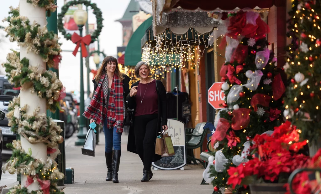 Zwei Frauen beim Weihnachtsshopping in der festlich dekorierten Main Street von Grapevine, Texas