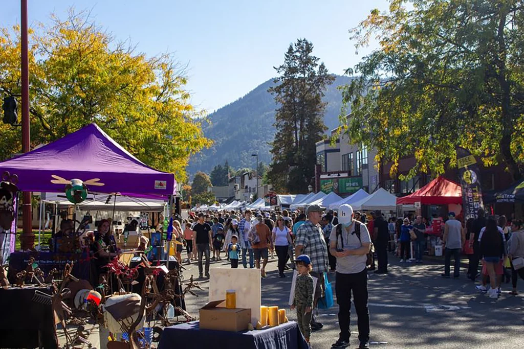 Menschenmenge bei den Salmon Days in Issaquah mit Marktständen und Tiger Mountain im Hintergrund.