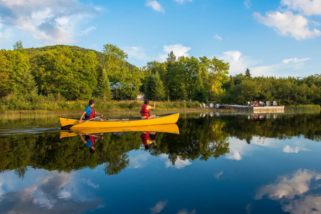 Zwei Personen paddeln im gelben Kanu auf einem stillen See im Parc national du Mont-Tremblant.