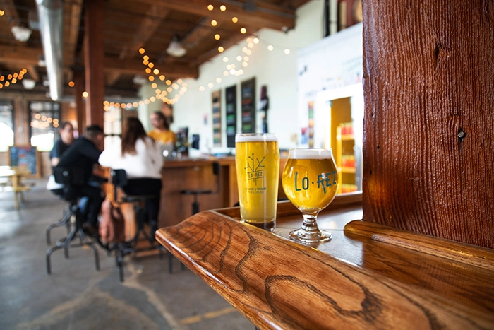 Zwei Gläser Craft-Bier in der Lo-Rez Brewery im Stadtteil Pilsen in Chicago, einer trendigen Mikrobrauerei mit gemütlicher Atmosphäre und Lichterketten.