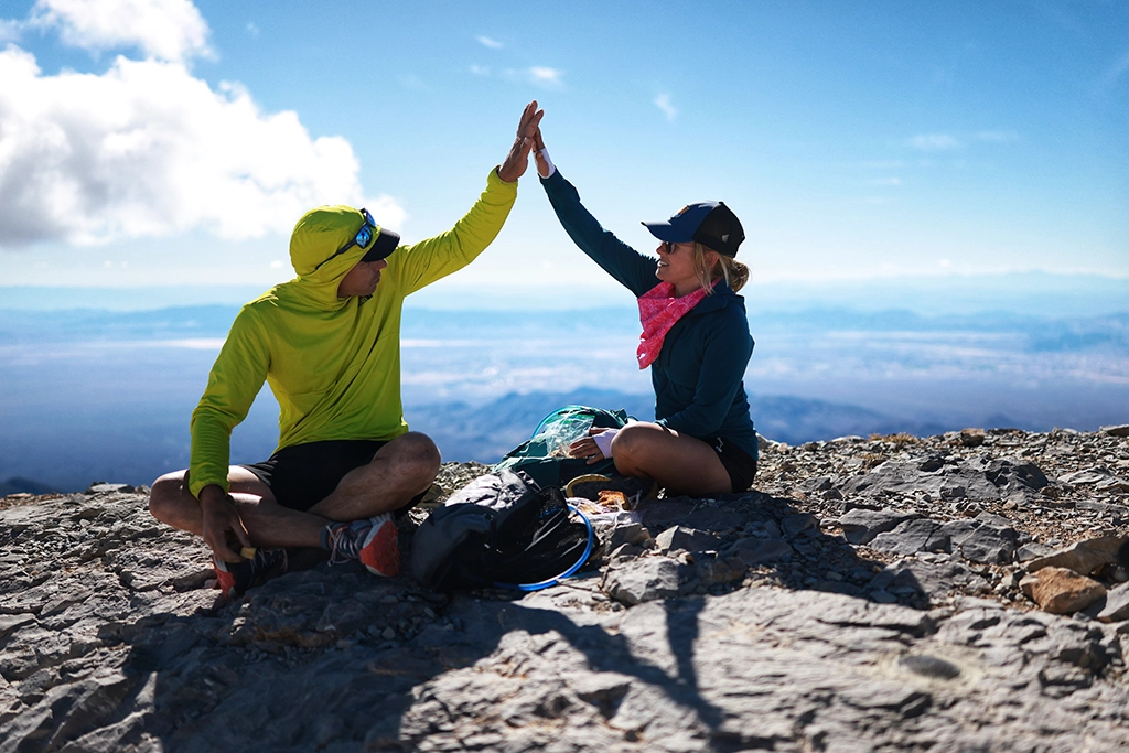 Alex Honnold und seine Frau Sanni McCandless geben sich ein High-Five auf einem Gipfel mit weitem Blick über die Nevada-Wüste.