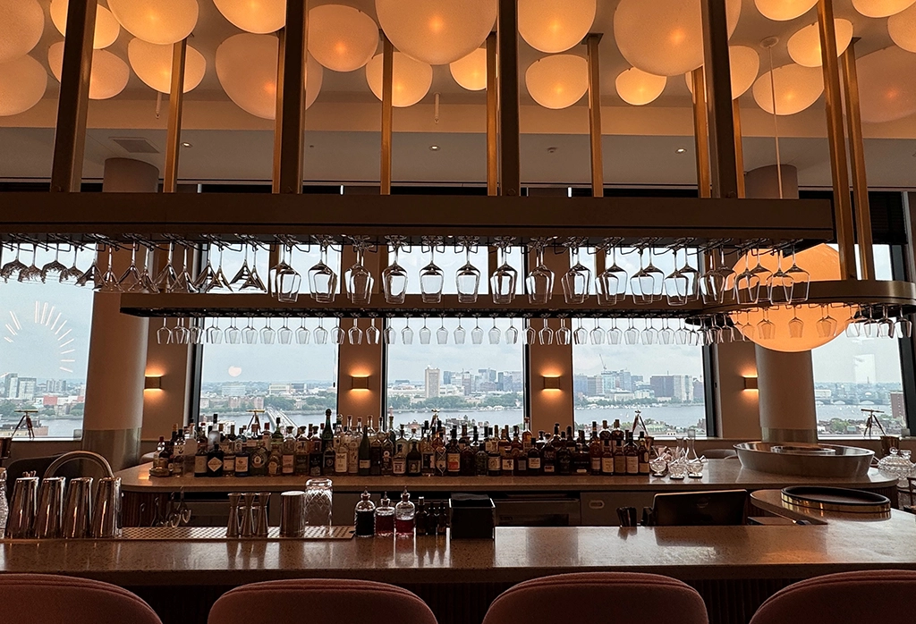 Stylische Bar mit Panoramablick auf Boston, Flaschenregal und hängenden Gläsern im Restaurant Bubble Bath.