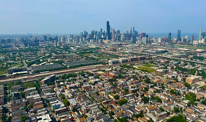 Blick aus einem Helikopter auf die Skyline von Chicago mit dem markanten Willis Tower und den weitläufigen Stadtvierteln im Vordergrund.