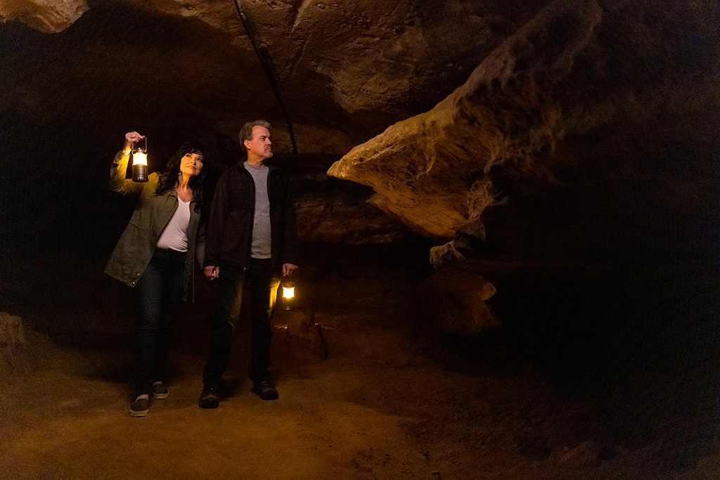 Ein Paar erkundet mit Laternen die dunklen Höhlen von Ruby Falls während einer nächtlichen Geistertour.