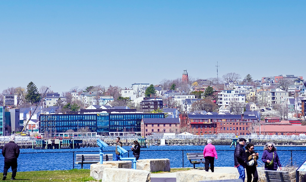 lick auf die Skyline von Portland, Maine, mit historischen Backsteinhäusern, modernen Gebäuden und Spaziergängern an der Waterfront.