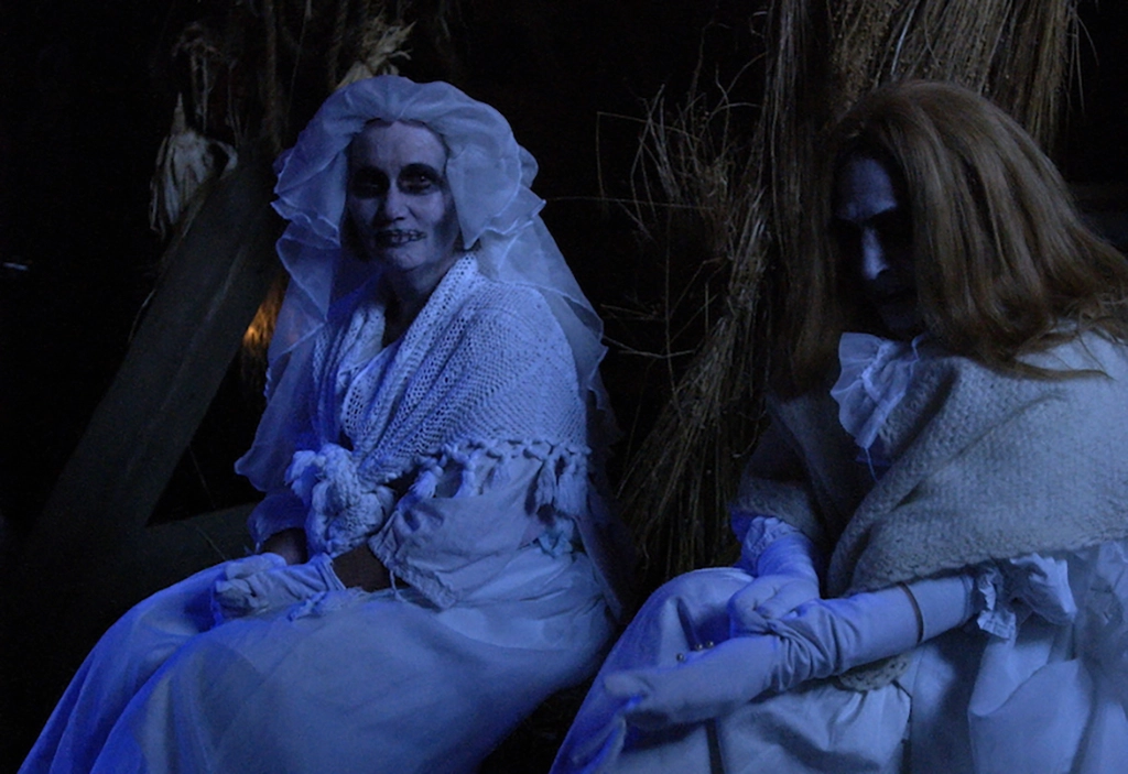 Zwei Schauspielerinnen in viktorianischen Geisterkostümen während einer nächtlichen Legendenführung in Sleepy Hollow.