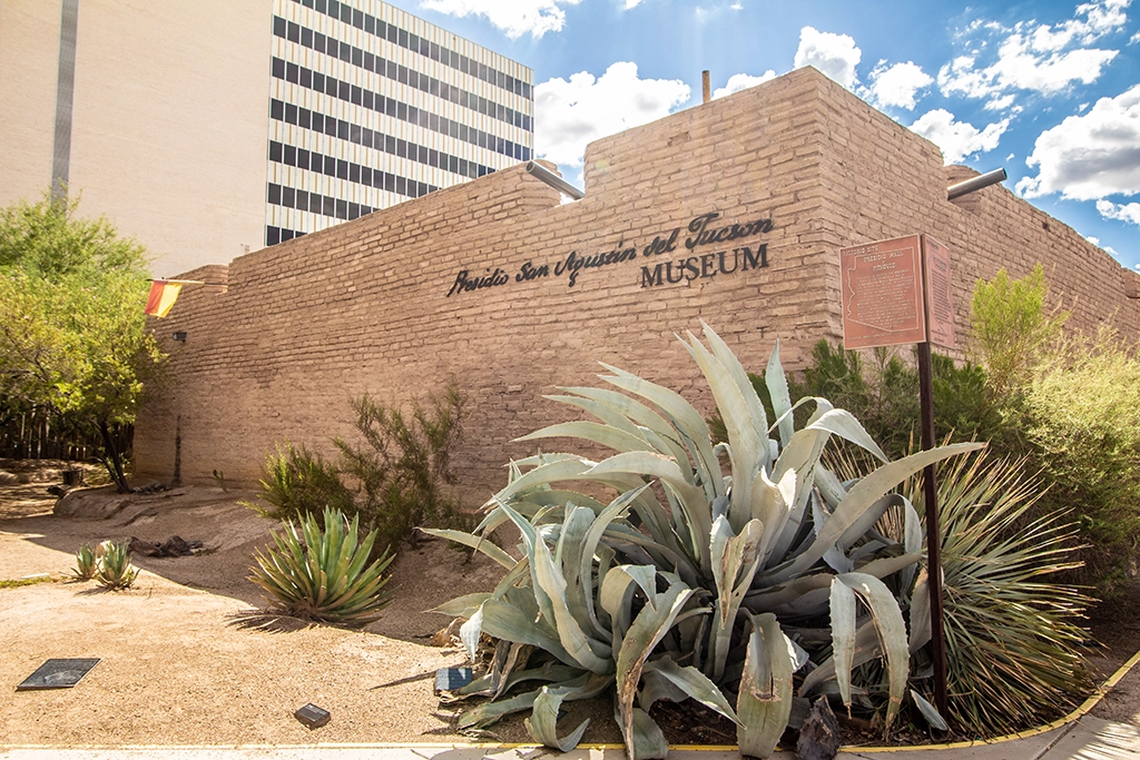 Exterior view of Presidio San Agustín del Tucson Museum with desert plants.