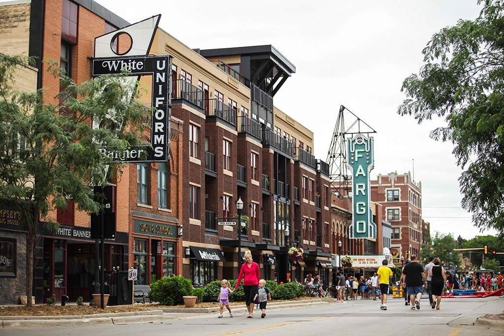 Menschen flanieren während des „Streets Alive“-Events durch die belebte Innenstadt von Fargo, North Dakota, vorbei am ikonischen Fargo Theatre.