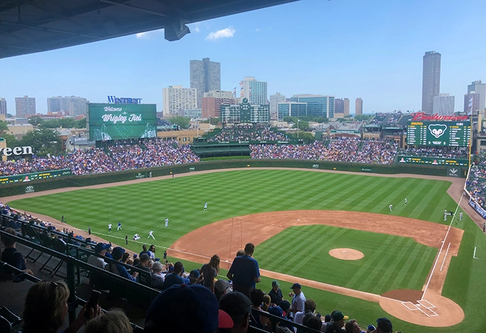 Blick ins Wrigley Field in Chicago, Heimstadion der Chicago Cubs, mit gefüllten Tribünen und Skyline im Hintergrund.