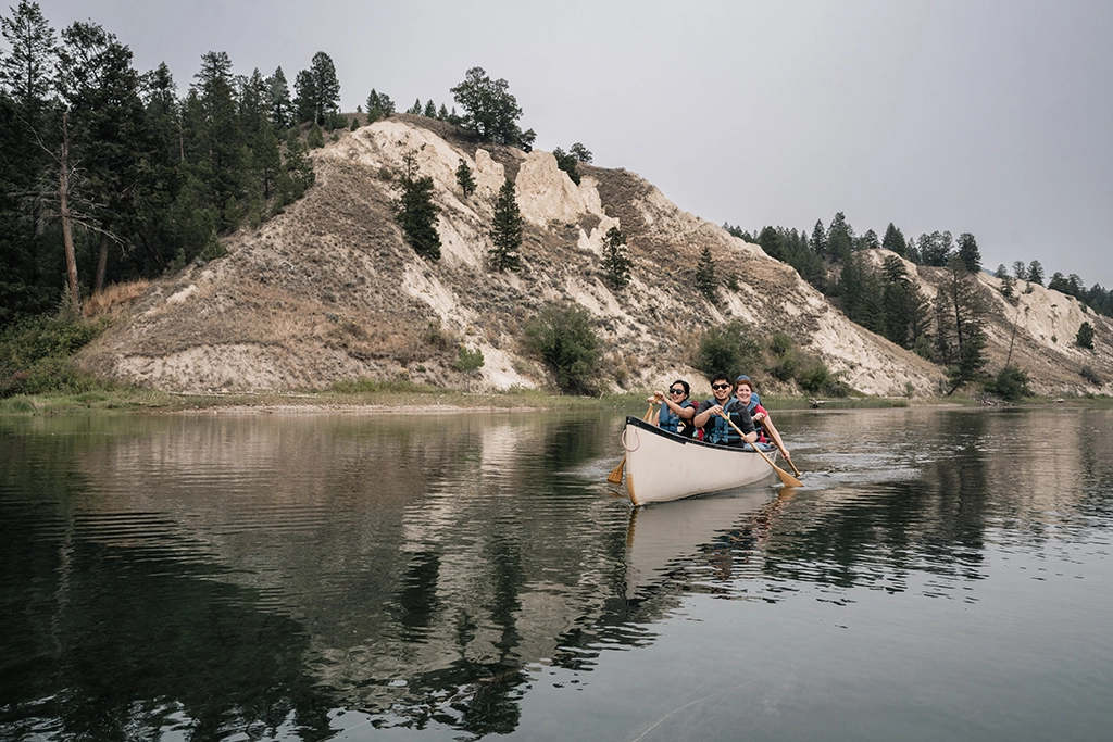 Zwei Personen paddeln auf einer geführten Tour über den Columbia River bei Invermere, umgeben von Sommerlandschaft.