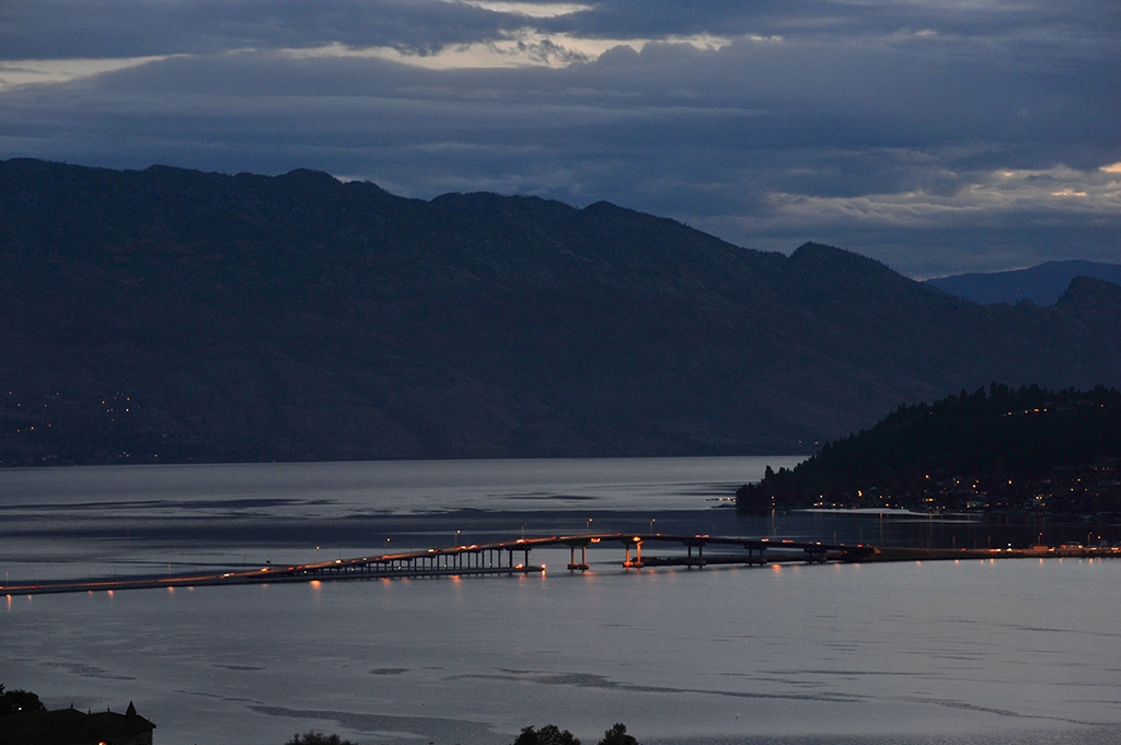 Abendaufnahme der beleuchteten William R. Bennett Bridge über den Okanagan Lake in Kelowna