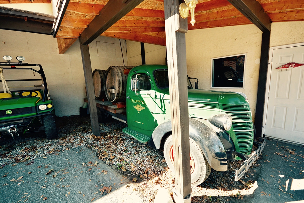 Grüner Oldtimer-Lieferwagen mit Holzfässern im Hof eines Weinguts bei Kelowna
