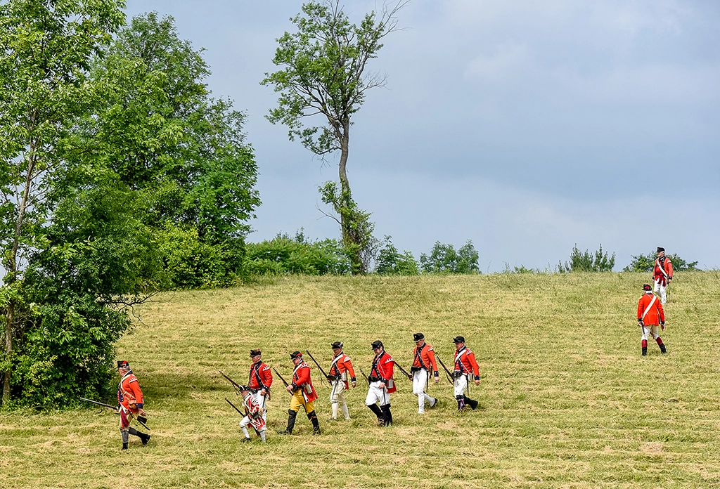 Reenactor-Gruppe in britischen roten Uniformen auf einer Wiese während einer historischen Nachstellung