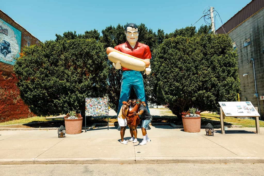 Besucher posieren vor der riesigen Paul-Bunyan-Statue mit Hotdog auf der Route 66