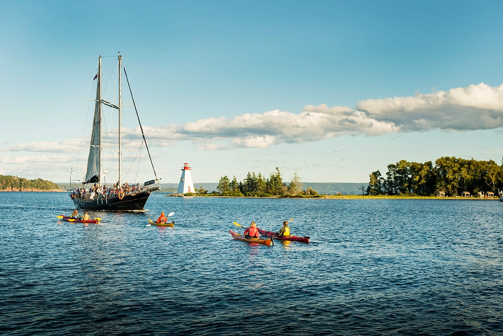Zwei Kajakfahrer paddeln vor Baddeck mit Blick auf den Kidston Island Lighthouse in Nova Scotia