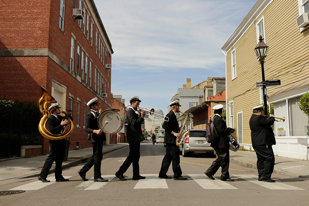 Eine traditionelle Brass Band marschiert durch das French Quarter von New Orleans – mit Tuba, Trommel und Bläsern.