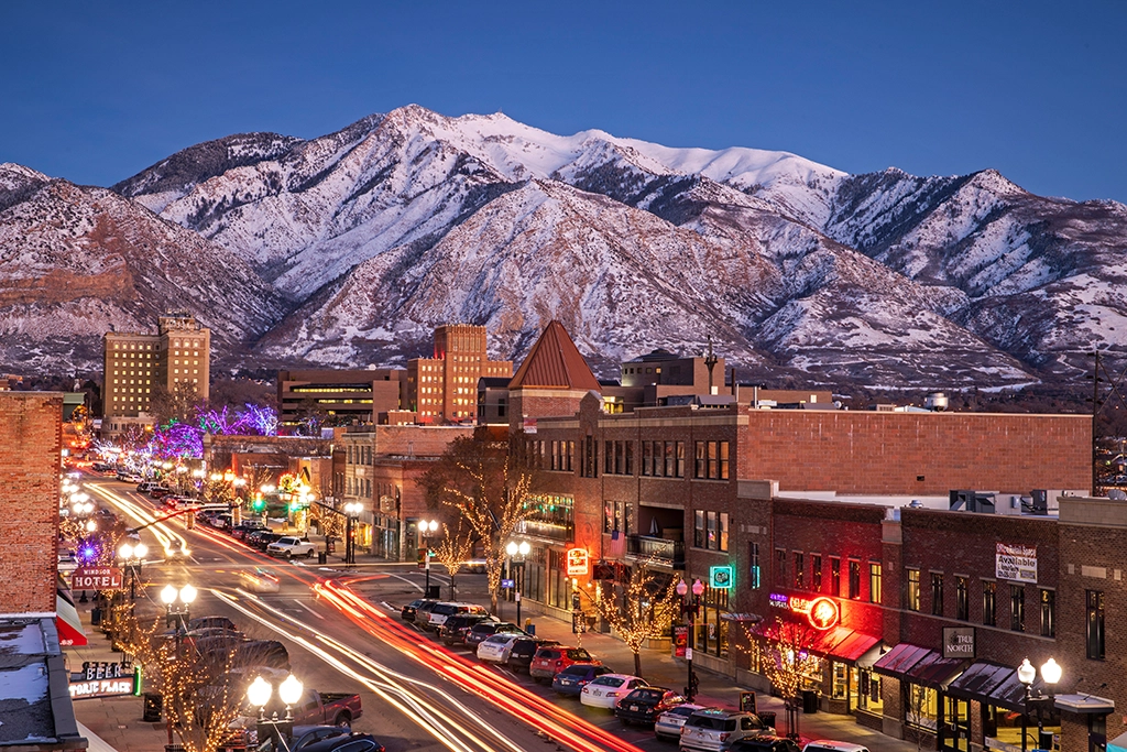 Winterliche Abendaufnahme der Stadt Ogden in Utah mit verschneiten Wasatch Mountains im Hintergrund